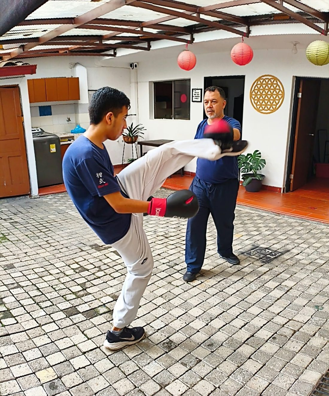 Harold González sosteniendo las manoplas para la patada de un alumno de kung fu